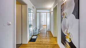 A hallway with wooden flooring, a glass railing, and a large floral artwork on the wall. - Honeycomb Chalets and Apartments Mozirje (Mozirje)