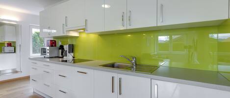 A modern kitchen with white cabinets, a green backsplash, and stainless steel appliances.