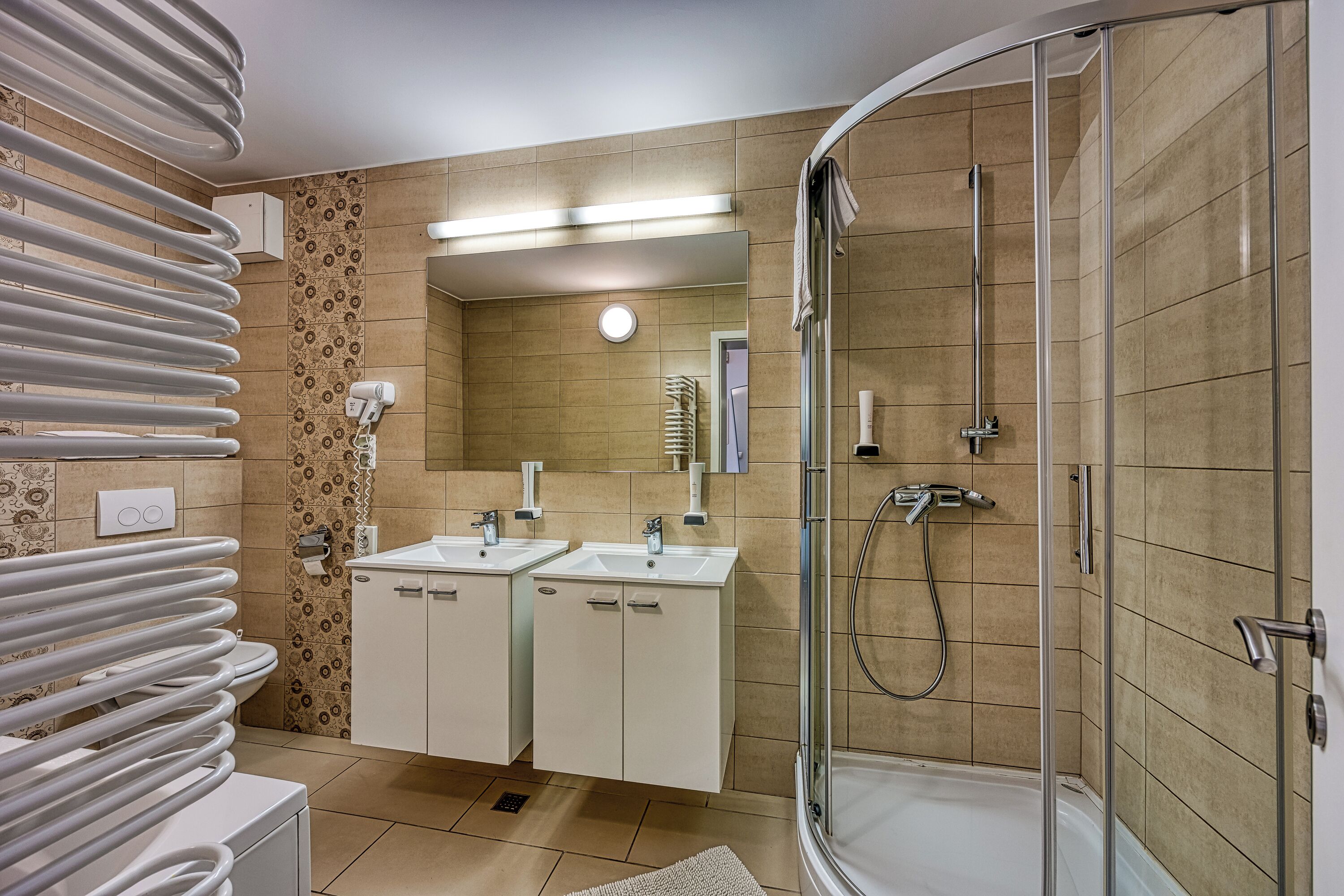 A modern bathroom with two sinks, a glass shower enclosure, and a towel rack.