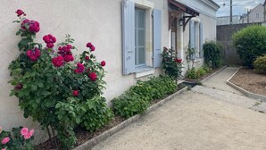 A building with a light-colored exterior, a small porch, and a pathway leading to the entrance. - Clos des Chardons - Le Jardin (Saint-Aignan)