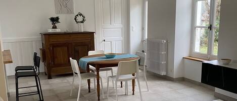 A spacious living room with a sofa, a glass coffee table, and a dining area with a table and chairs.