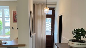 A narrow hallway with a wooden counter, a black chair, a potted plant, and a door leading to another room. - Clos des Chardons - Le Jardin (Saint-Aignan)