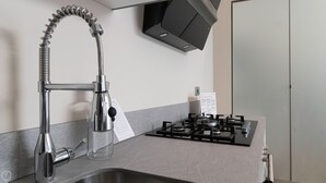 A kitchen with a stainless steel faucet, a gas stove, and a black range hood. - Italianway Easy - Naviglio Pavese 6 (Milan)