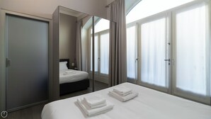 A hotel room with a bed, a nightstand, a mirror, and a door. - Italianway Easy - Naviglio Pavese 6 (Milan)