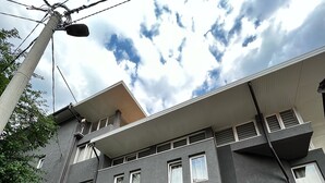 Ein mehrstöckiges Gebäude mit dunkler Fassade, zahlreichen Fenstern und einem Steinsockel.