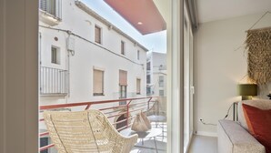 Un balcon avec des fauteuils en osier, une petite table et un canapé.