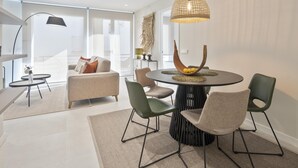 Un espace de salle à manger moderne avec une table ronde, des chaises vertes et un luminaire suspendu original.