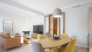 A modern living room with a sofa, TV, fireplace, and dining area with chairs and a table.