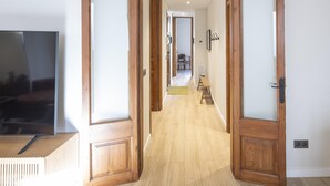 A hallway with wooden doors, a bench, and a TV on a stand.