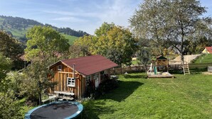 A wooden house with a red roof, a trampoline, and a wooden deck. - Family-friendly temporary home (Horben)