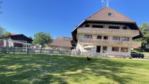 A two-story building with a balcony, a fenced yard, and a clear blue sky. - Family-friendly temporary home (Horben)