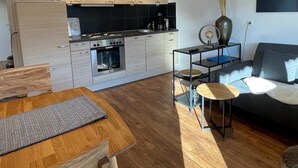 A modern kitchen with wooden cabinets, a built-in oven, and a dining area with a wooden table and chairs. - Family-friendly temporary home (Horben)