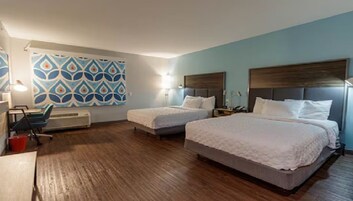 A hotel room with two beds, a desk, and a chair.
