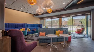 A modern lounge area with seating, a hanging chair, and pendant lighting.