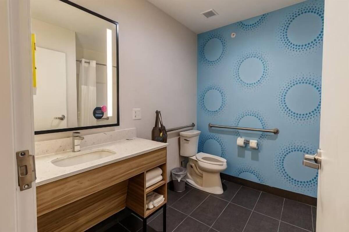 A bathroom with a sink, mirror, toilet, and a blue patterned wall.