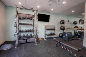A gym with a pull-up bar, dumbbells, kettlebells, a bench, and a mirror. - Tru By Hilton Mckinney (McKinney)