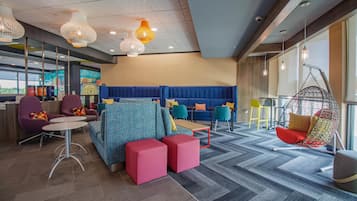 Un espace de détente moderne, aménagé avec des sièges confortables, un fauteuil suspendu et une fresque murale.