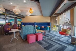 A modern lounge area with seating arrangements, a hanging chair, and a mural on the wall. - Tru By Hilton Mckinney (McKinney)