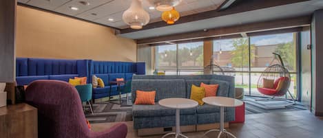 A modern lounge area with seating, a hanging chair, and pendant lighting.