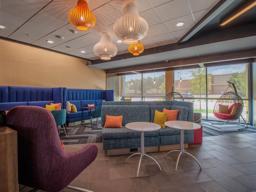 A modern lounge area with seating, a hanging chair, and pendant lighting.