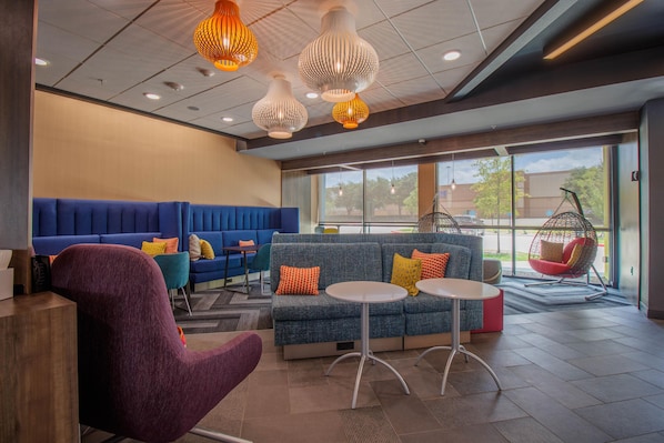 A modern lounge area with seating, a hanging chair, and pendant lighting. - Tru By Hilton Mckinney (McKinney)