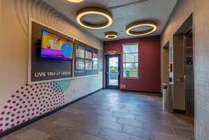 A hallway with a TV screen, exit signs, and a trash can.
