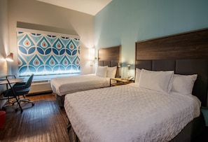 A hotel room with two beds, a desk, a chair, and a patterned wall. - Tru By Hilton Mckinney (McKinney)