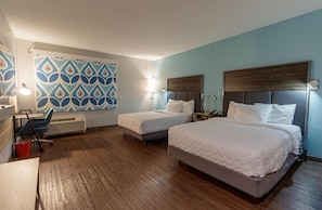 A hotel room with two beds, a desk, a chair, a red bucket, and a patterned wall. - Tru By Hilton Mckinney (McKinney)
