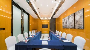 A conference room with a long table, white chairs, and a large screen. - Madison Hotel Taizhou Jingqi (Taizhou)
