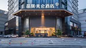 A modern hotel entrance with a glass facade, a covered entrance area, and a parking lot with bollards. - Madison Hotel Taizhou Jingqi (Taizhou)