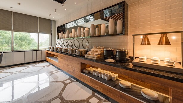 A modern kitchen with a wooden countertop, a variety of kitchenware, and a large window providing a view of greenery outside. - Madison Hotel Taizhou Jingqi (Taizhou)