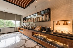 Una cucina moderna con un piano di lavoro in legno, diversi utensili da cucina e un'ampia finestra che offre vista sul verde.