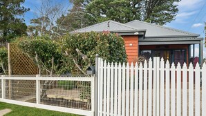 Uma casa residencial com quintal cercado, deck de madeira e garagem.