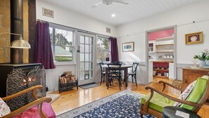 Uma sala de estar aconchegante com lareira, móveis de madeira, uma mesa de jantar e uma área de cozinha com prateleiras.