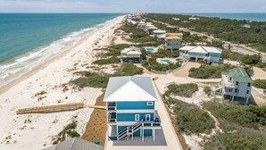 A coastal property with multiple houses, a beach, and a clear view of the ocean.