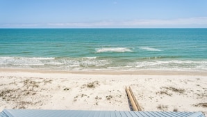 A beach with a wooden boardwalk leading to the water.