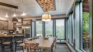 Cozinha moderna com armários de madeira, geladeira de aço inoxidável e um espaço de jantar com mesa e cadeiras de madeira.
