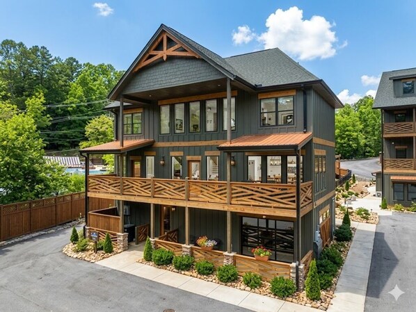 A two-story building with a balcony, a covered porch, and a stone foundation.