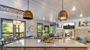 A spacious kitchen with a large island, pendant lighting, and a rustic stone wall.