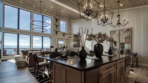 Een ruime keuken met een groot eiland, houten kasten en uitzicht op de oceaan.