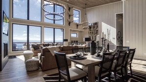 Een ruime woonkamer met een grote eettafel, comfortabele zithoek en uitzicht op de oceaan.