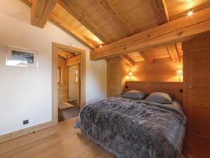 Una camera accogliente con travi in legno, un letto con una coperta soffice, una lampada da comodino e un quadro appeso al muro.