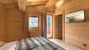 Une pièce de cabane en bois comprenant un lit, une fenêtre, un radiateur et une porte donnant sur l’extérieur.