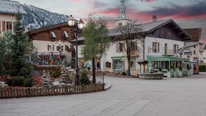 Une place bordée de bâtiments, avec un beffroi et un mur de pierre.