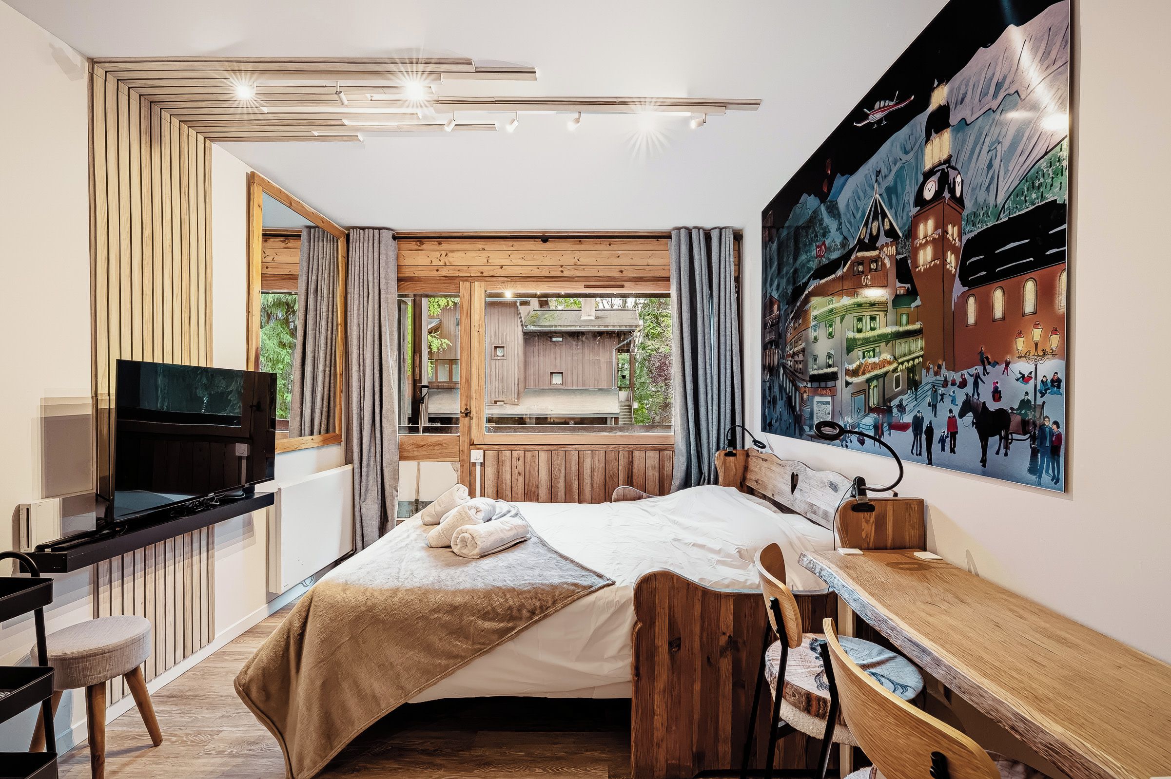 Een moderne slaapkamer met een bed, een bureau, een televisie en een groot raam.