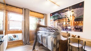 Une pièce comprenant un lit, un bureau et une chaise. Il y a une fenêtre avec des rideaux et une vue sur l’extérieur.