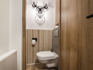 A modern bathroom with a wooden panel wall, a toilet, and a wall-mounted toilet paper holder. - Studio l'Orée - City centre - Megève (Megève)