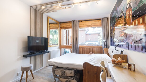 Une chambre moderne avec un lit, une télévision, un bureau avec une tasse et une fenêtre avec des rideaux.
