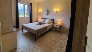 Un dormitorio con cama, mesitas de noche, un espejo y una ventana con cortinas.