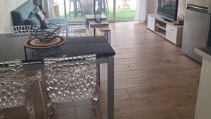Un grand espace de vie comprenant une table à manger, des chaises, un canapé, un téléviseur et un réfrigérateur.